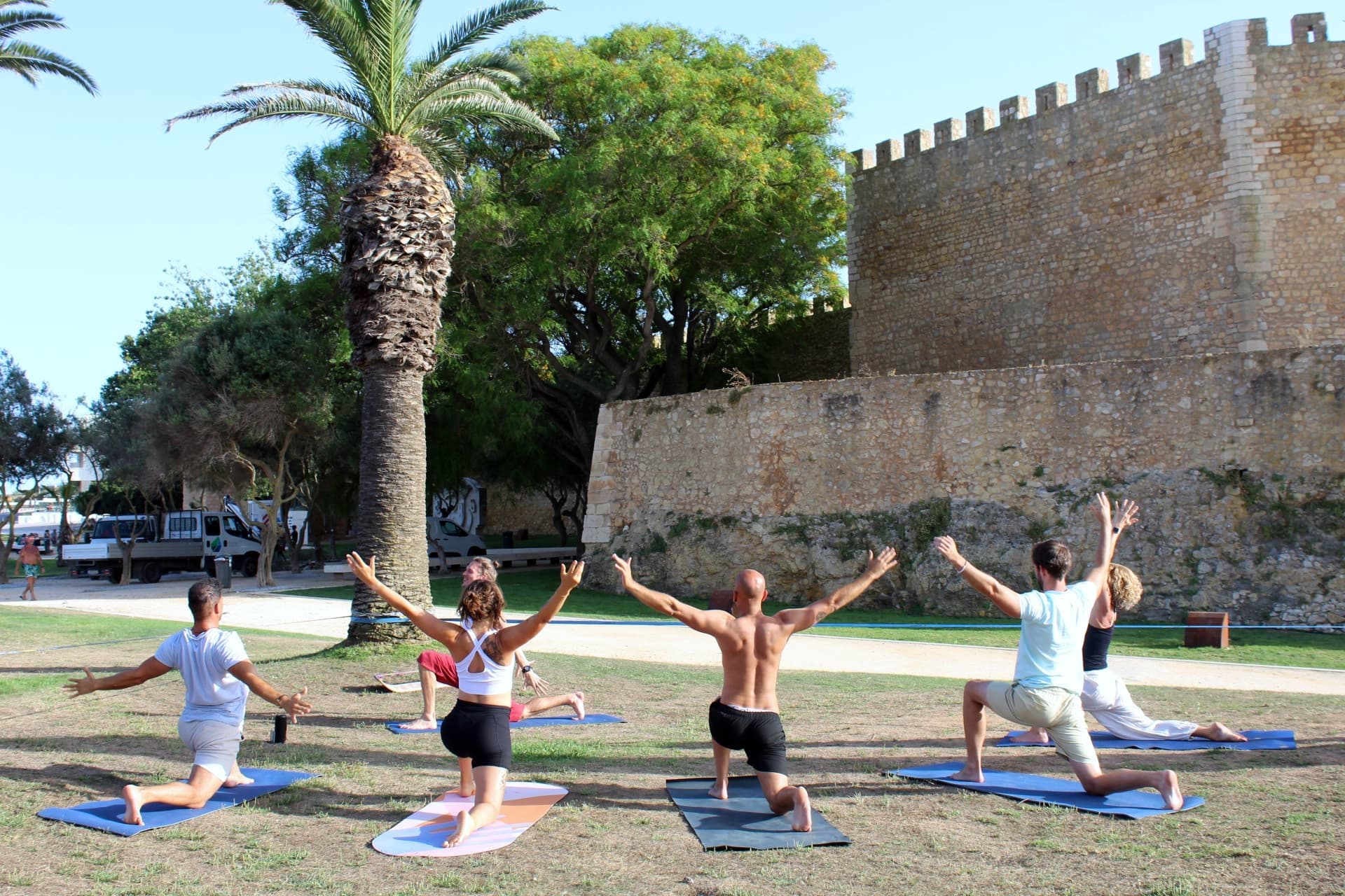 Outdoor group yoga session near historic castle and palms