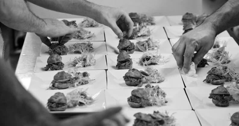 Chefs plating small bites in professional kitchen during food tour