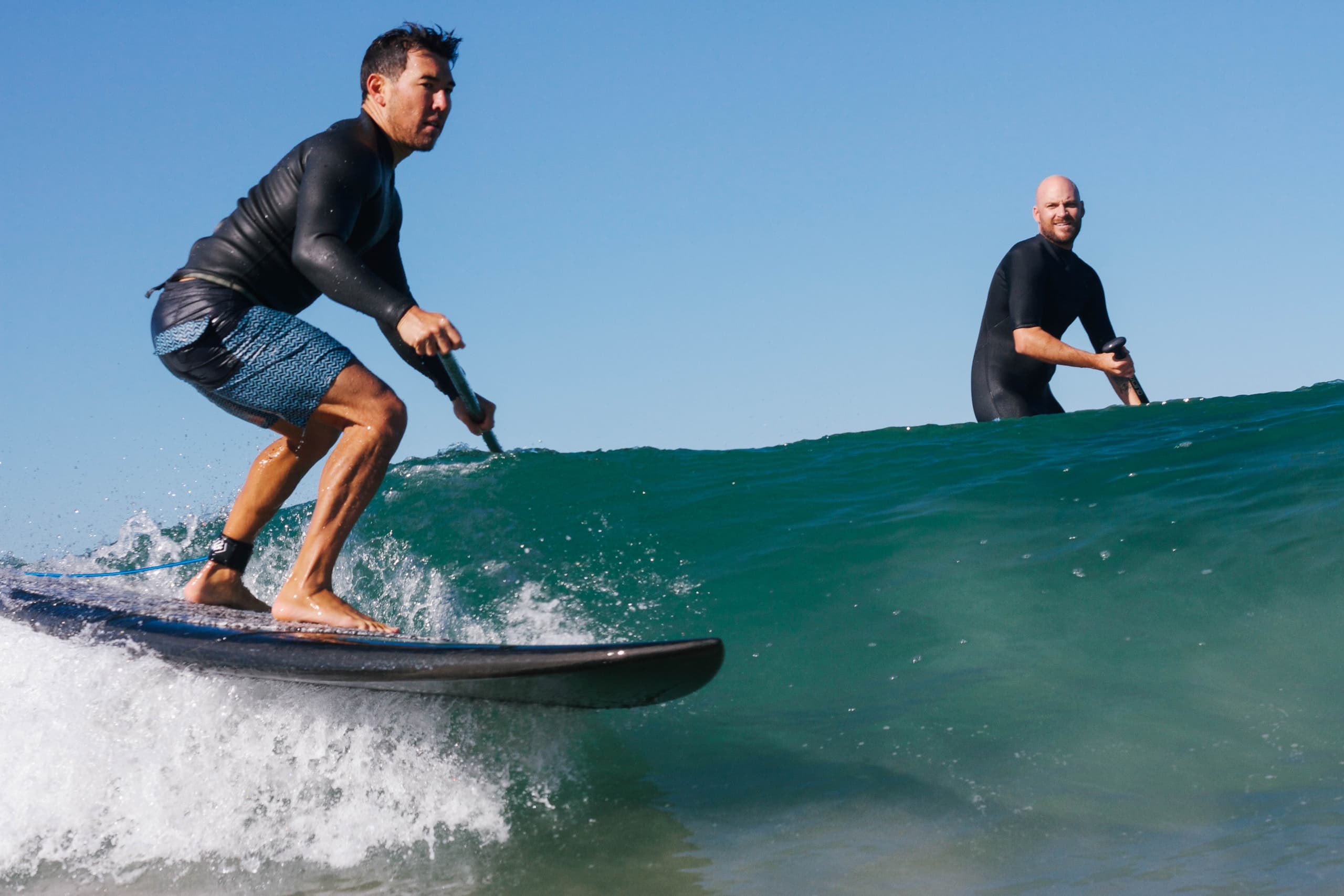 Surfer riding ocean wave on standup paddleboard, coastal surf