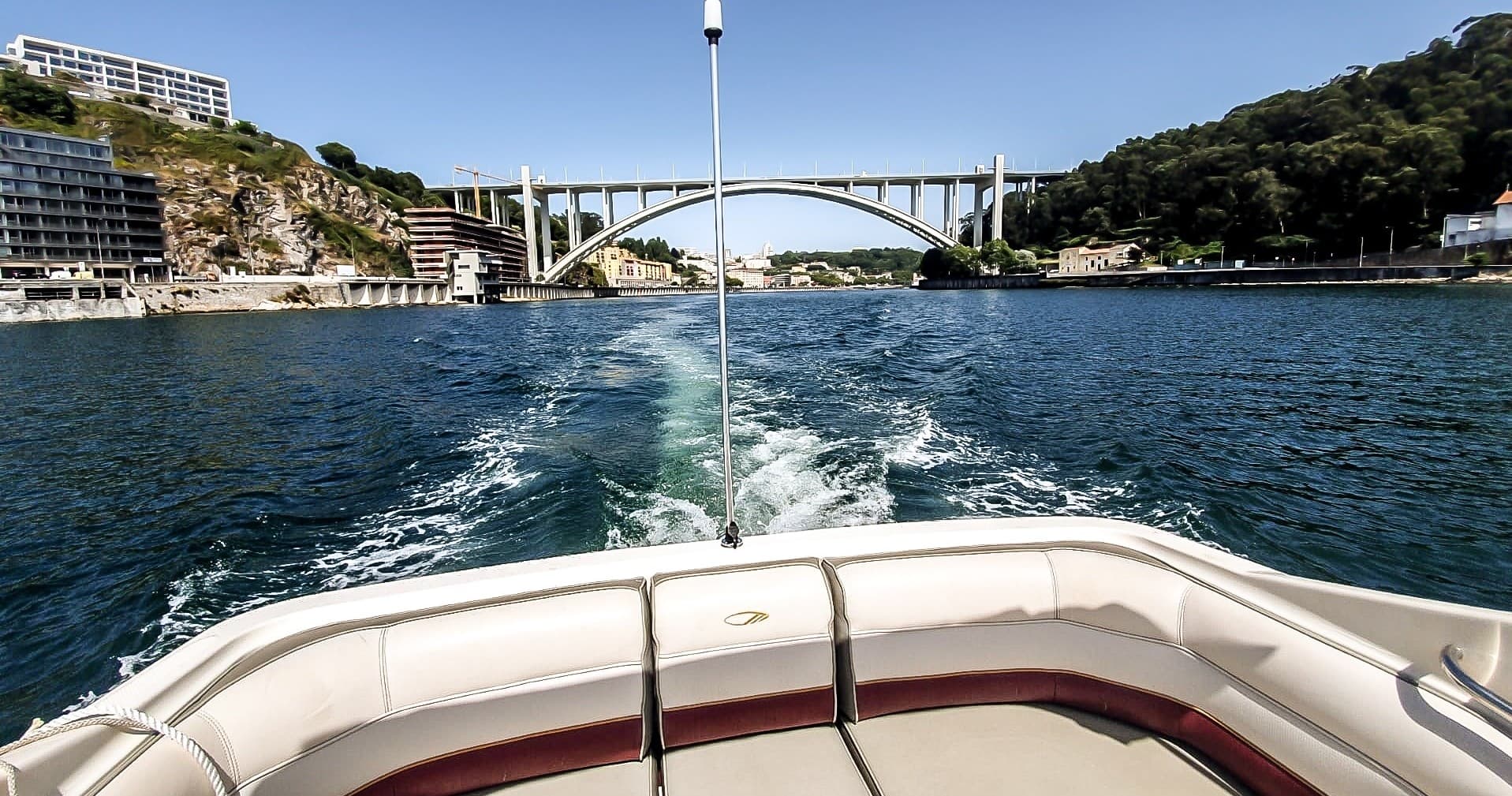 View from boat stern passing bridge over scenic river in Porto