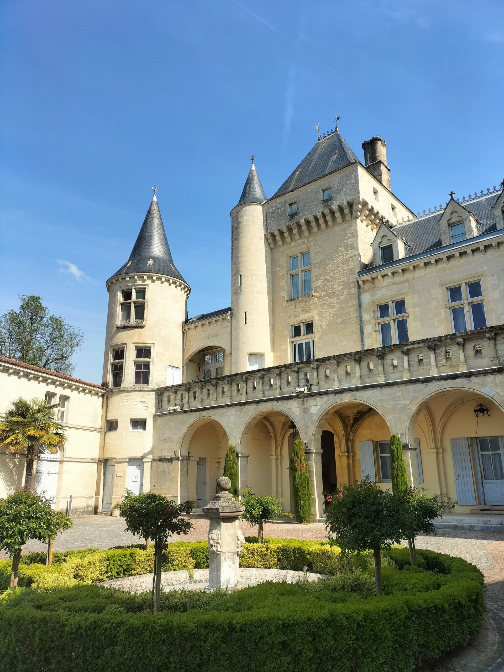 Historic chateau courtyard with arched galleries and manicured garden