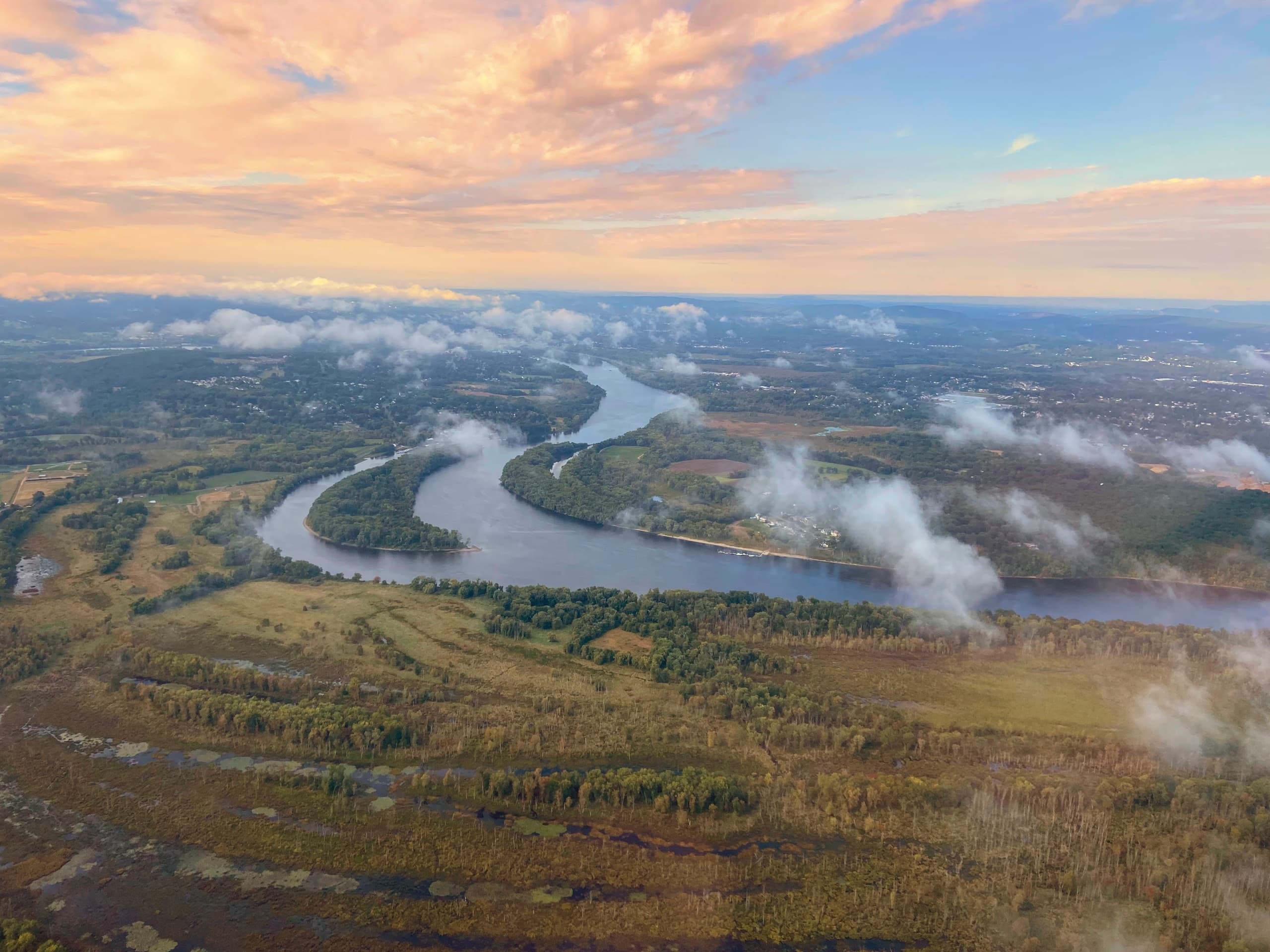 Sunrise aerial over winding river, marshland and wetlands