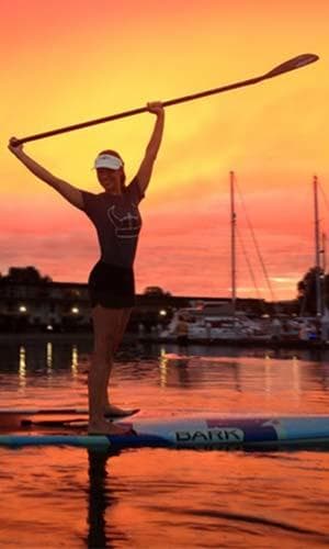 Silhouette stand-up paddleboarder posing at colorful sunset
