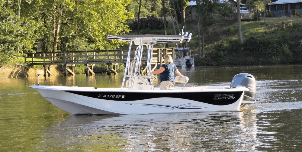 Center console fishing boat near wooded shoreline on calm river