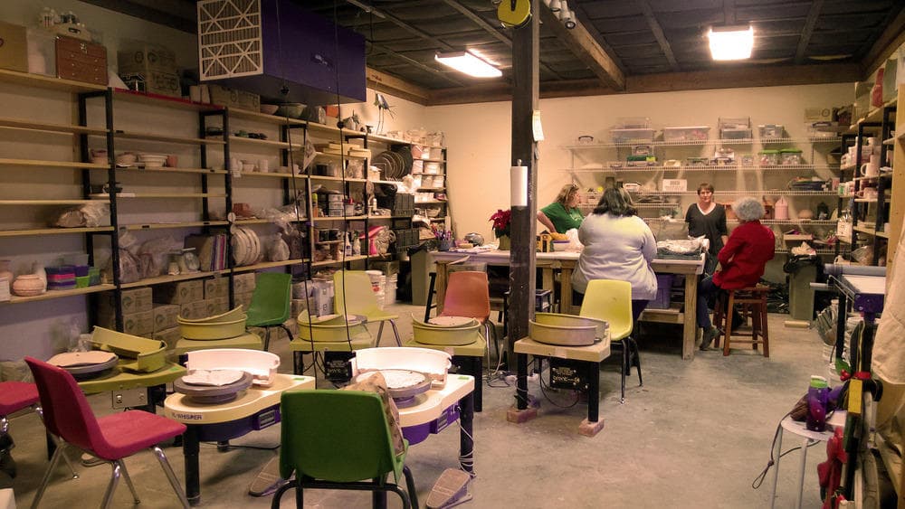 Pottery studio interior with students at wheels learning throws