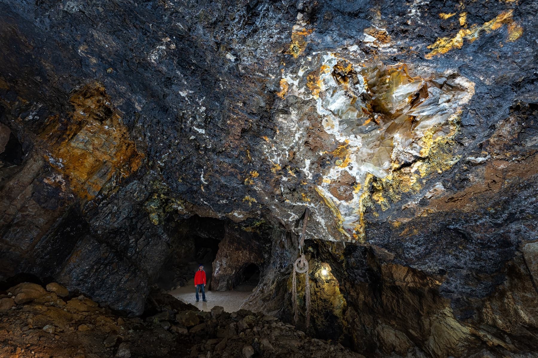 Caver exploring mineral-rich cave chamber on guided spelunking