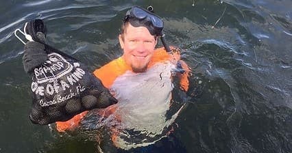 Snorkeler emerging from water holding catch bag during nearshore dive