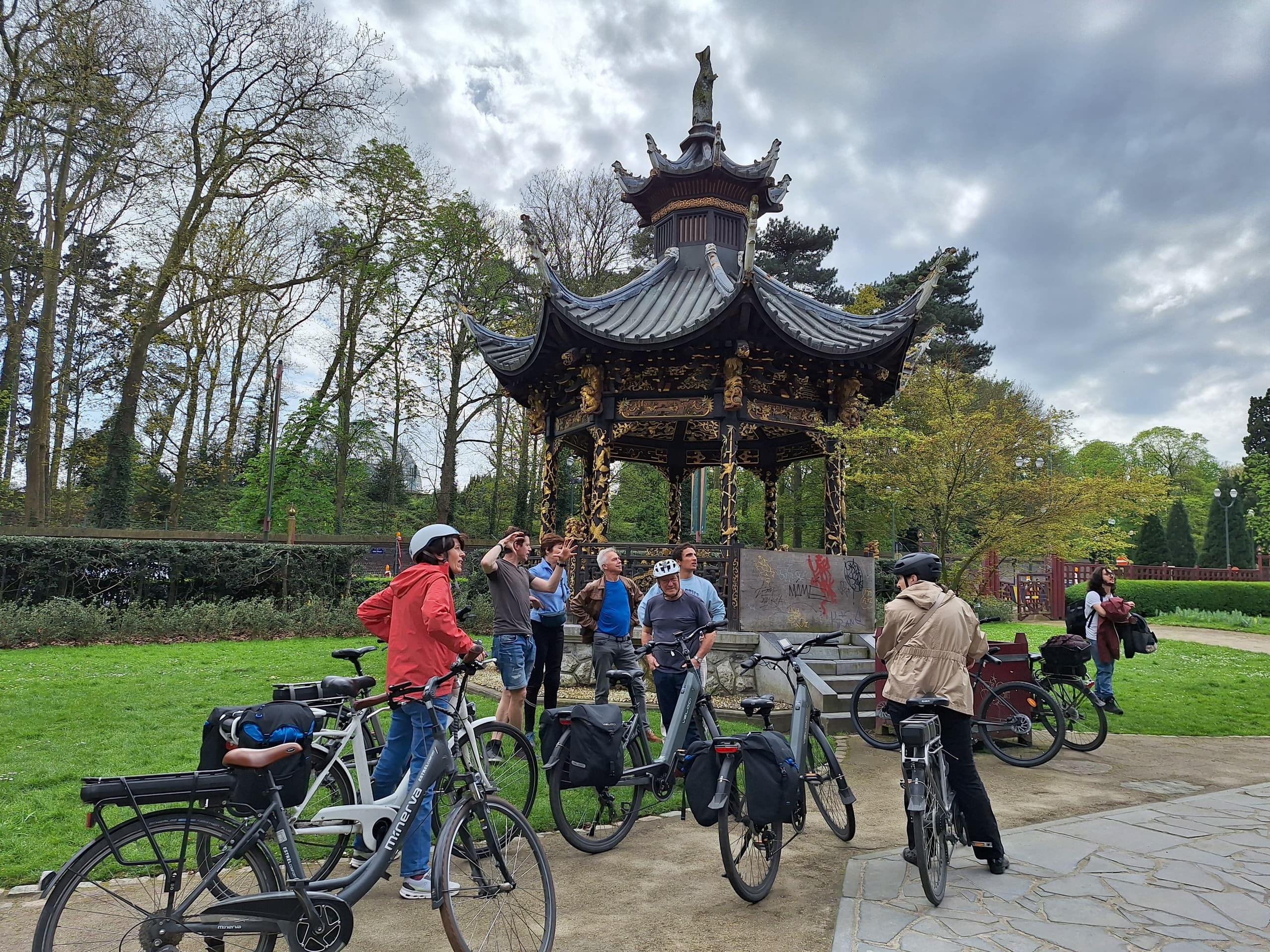 Guided bike tour gathering by ornate park pavilion in city park