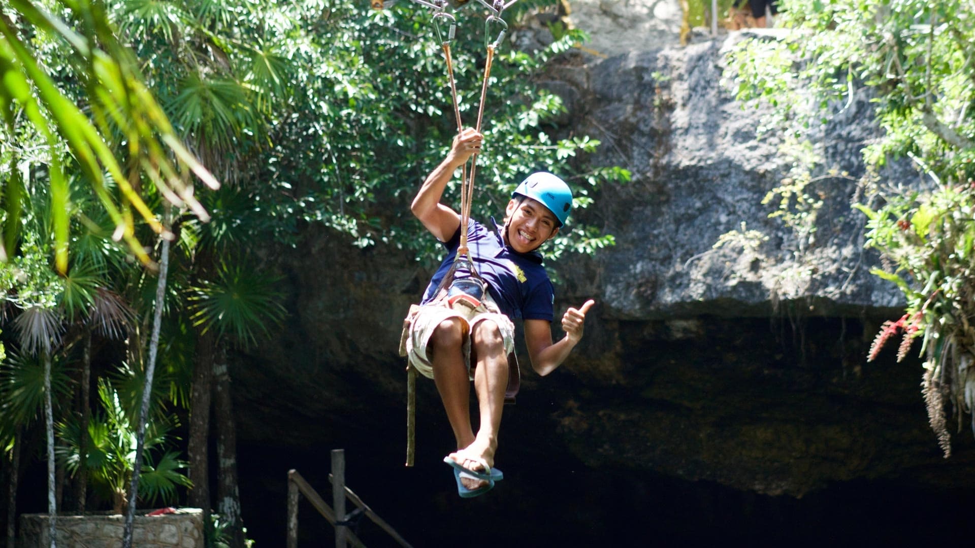 Person ziplining over lush tropical jungle cenote in Mexico