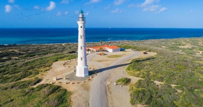 Aerial coastal lighthouse on dunes overlooking turquoise ocean