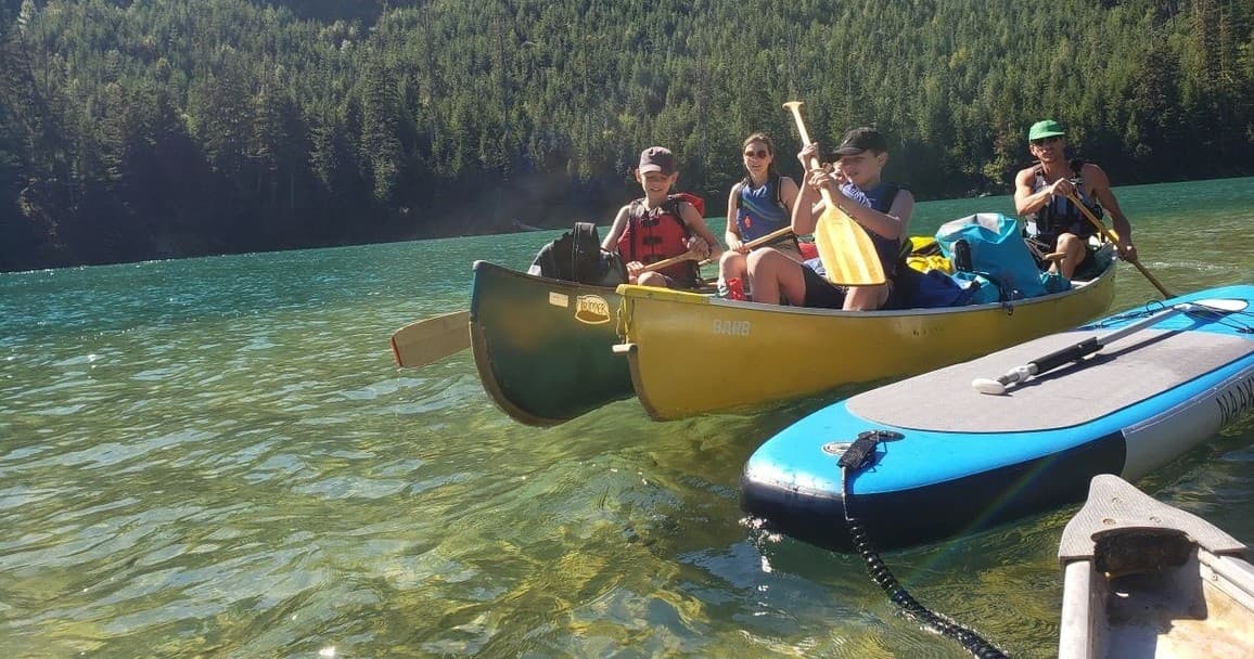 Group canoe and paddleboard exploring clear mountain lake