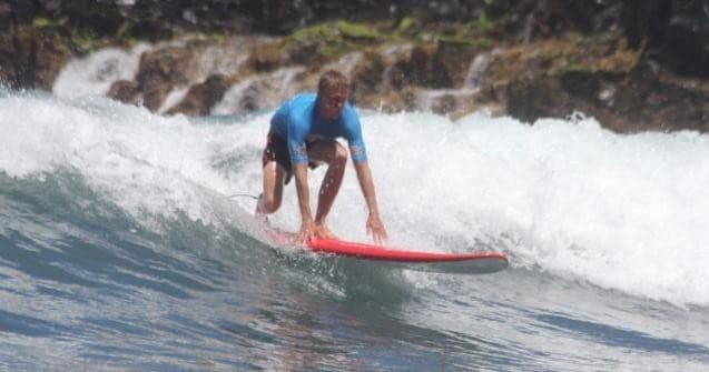 Surfer riding a breaking wave on open ocean near cliffs