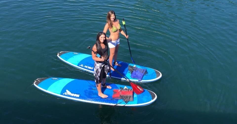Two standup paddleboarders paddling on clear deep blue lake water