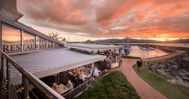Harborside restaurant and marina promenade at sunset, waterfront dining
