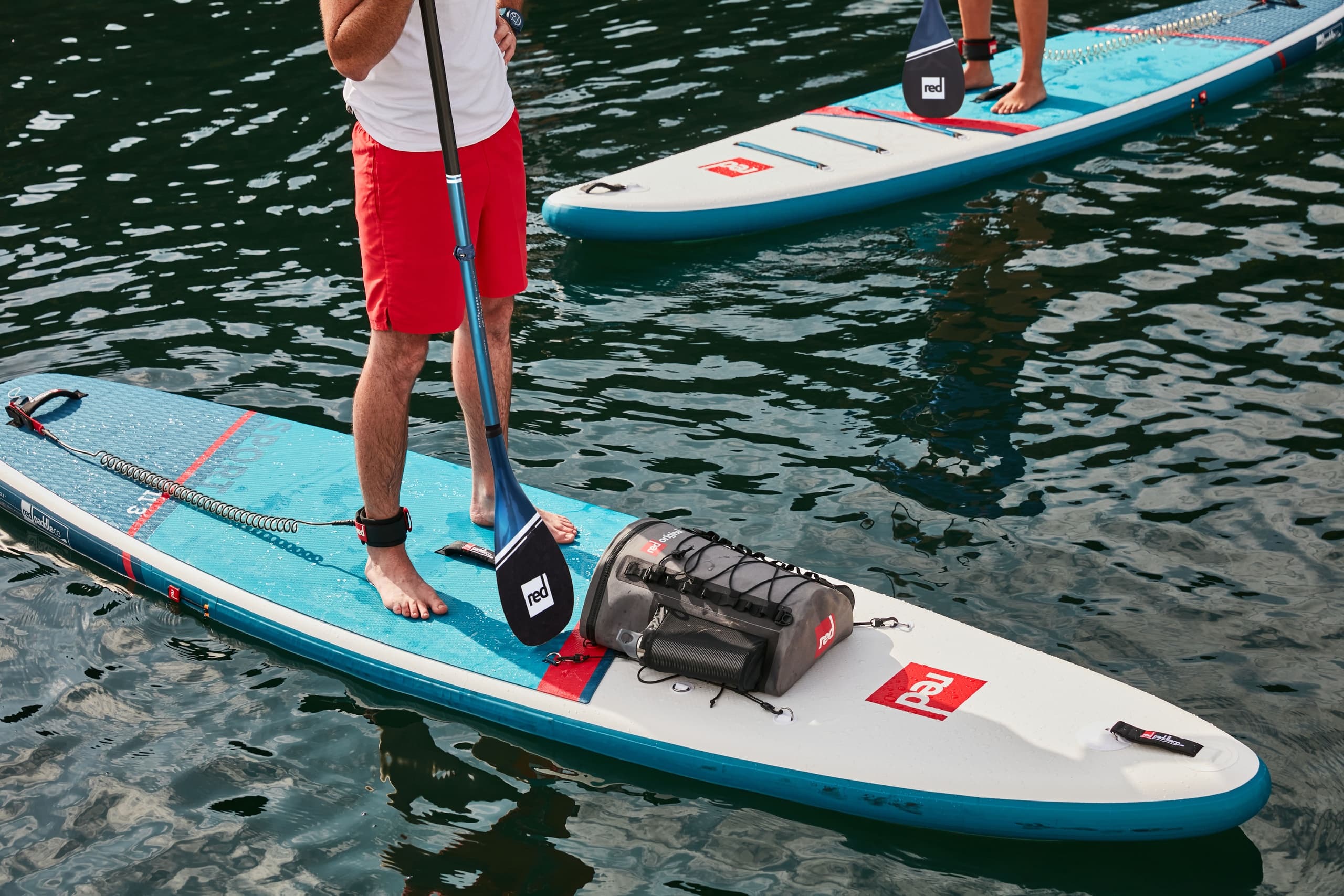 Close-up paddleboard with rider standing on calm harbor water