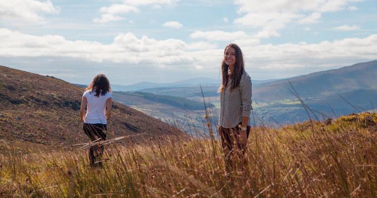 Backpackers walking grassy mountain ridge, outdoor hill trek
