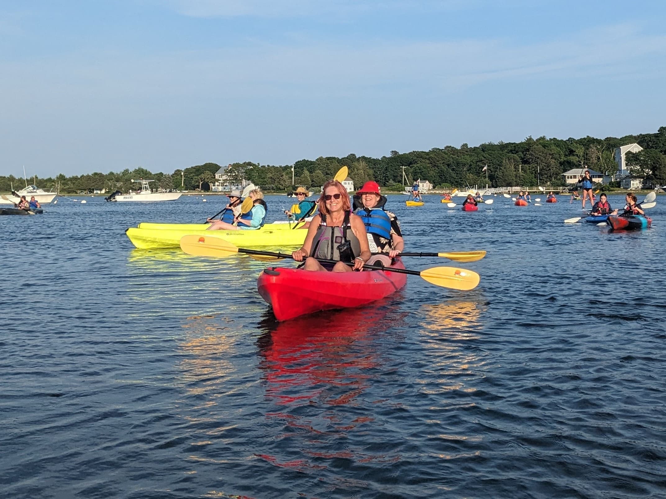 Large mixed-age kayak flotilla paddling across Buzzards Bay