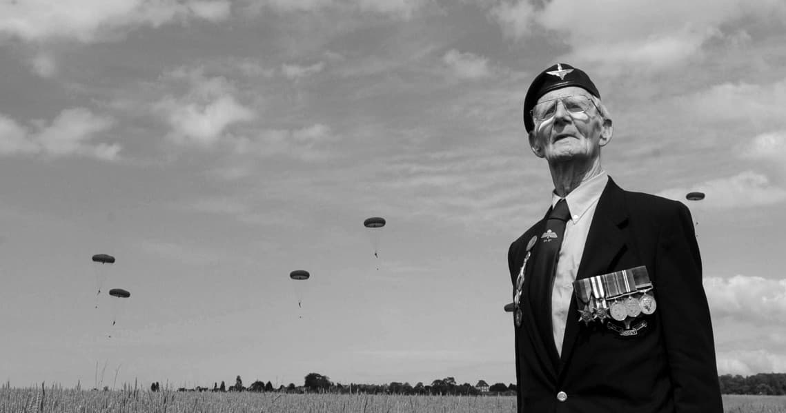 Veteran watching paratroopers descend over historic open battlefield