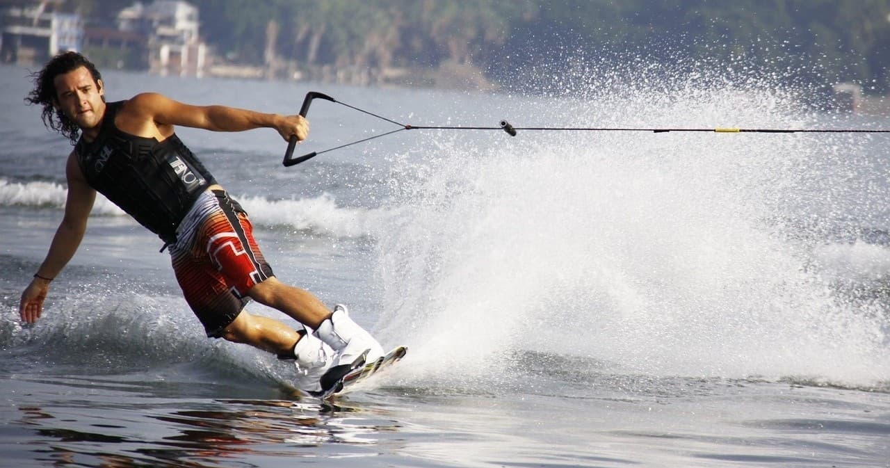 Wakeboarder cutting through spray on lake at sunny resort