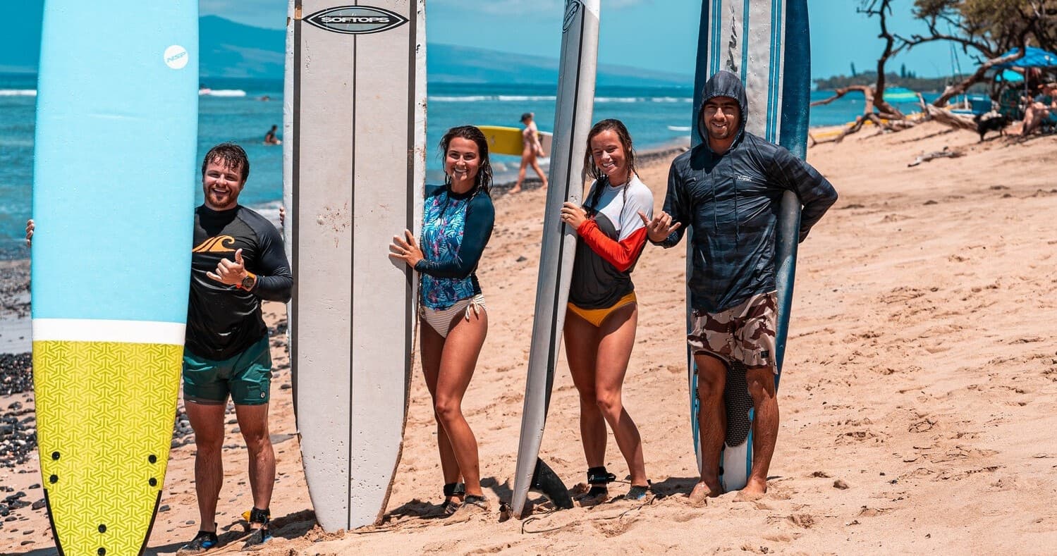 Surfers posing with longboards on sunny Maui sandy beach