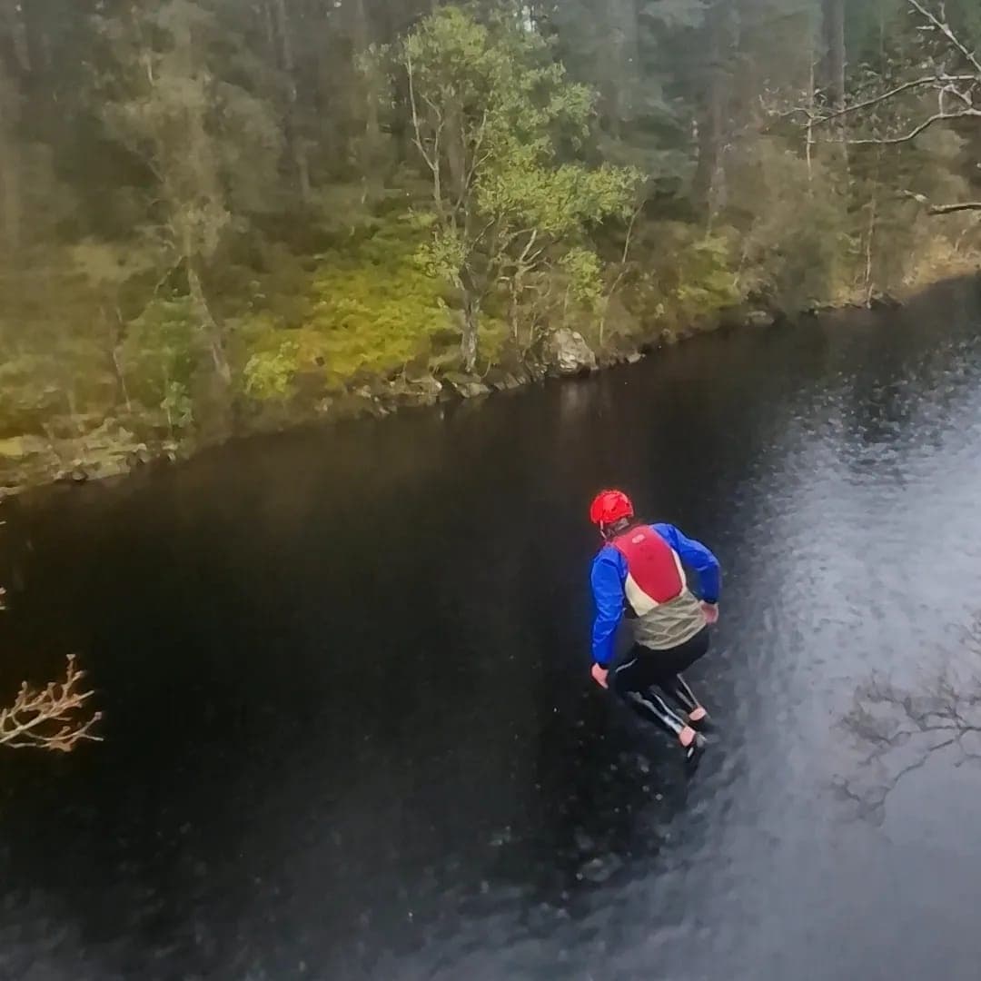 Person in lifejacket jumping into remote river under trees