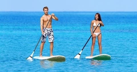 Couple standup paddleboarding on calm turquoise ocean in Hawaii