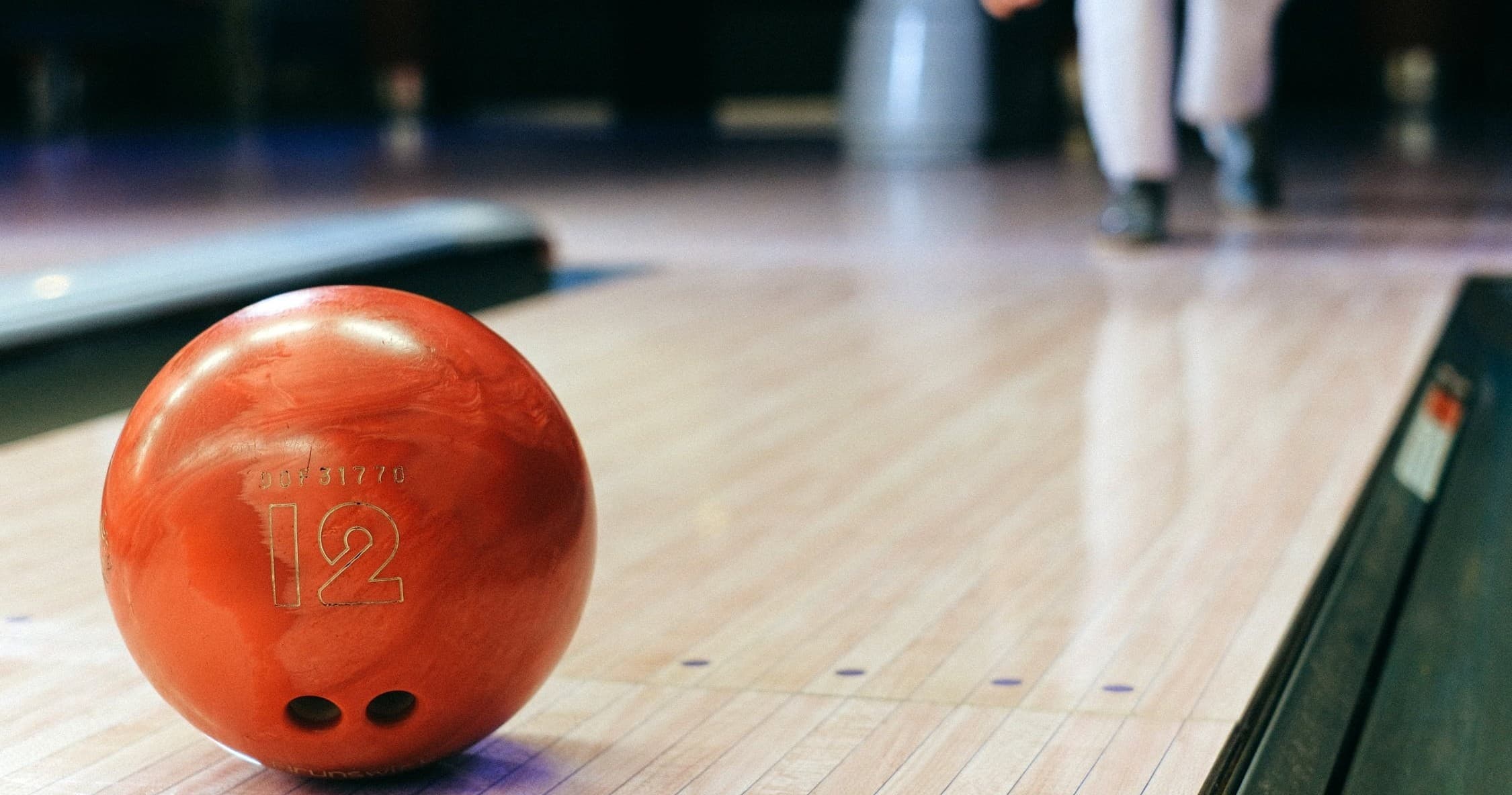 Close-up red bowling ball rolling down polished indoor lane