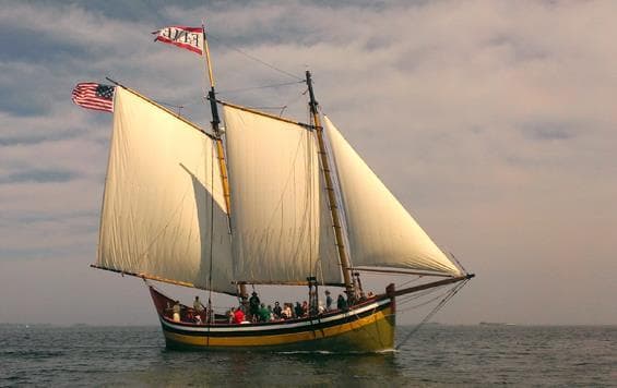 Historic schooner under full sail cruising calm coastal waters