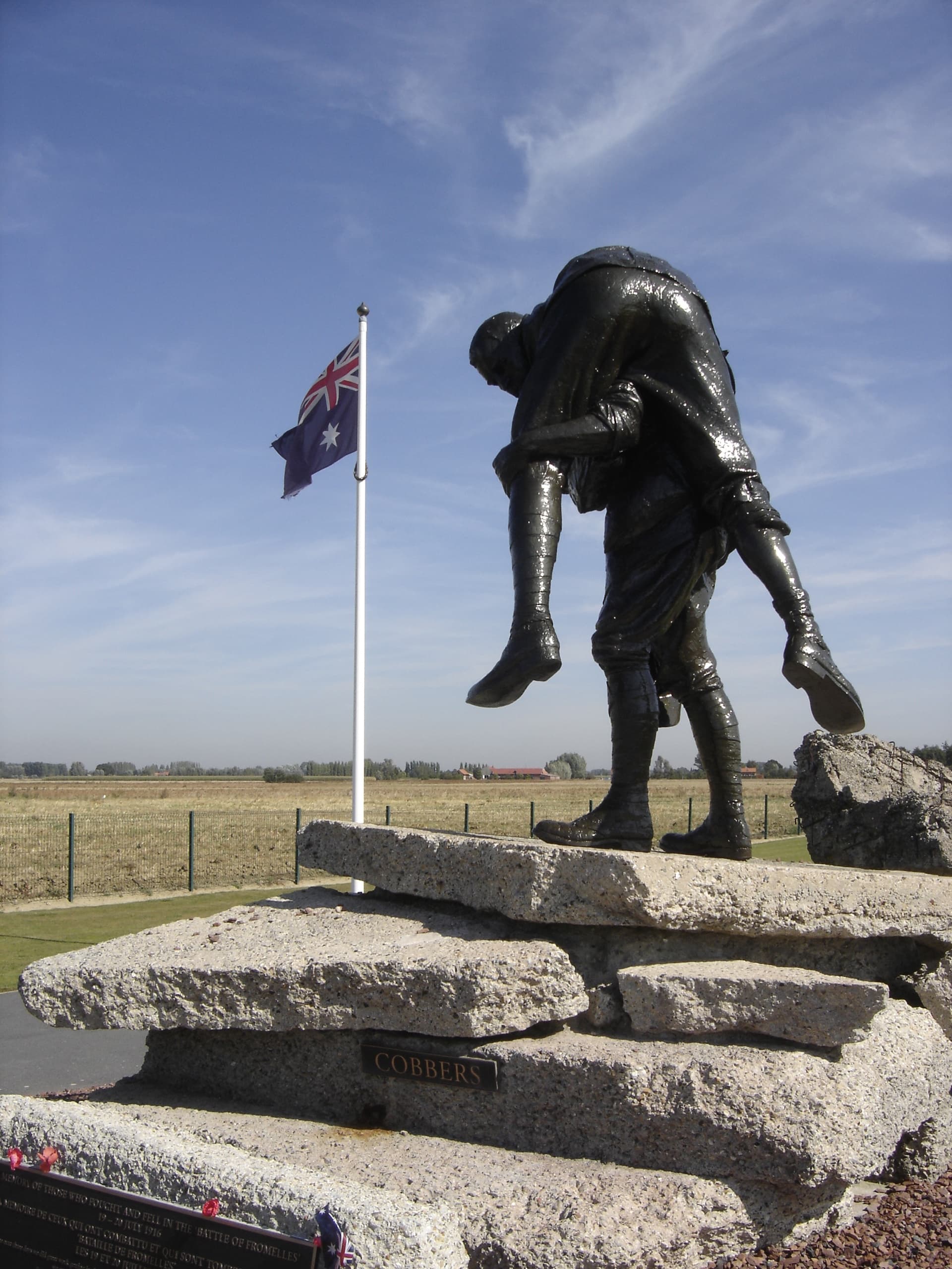 Soldier carrying wounded comrade statue with flag at memorial grounds
