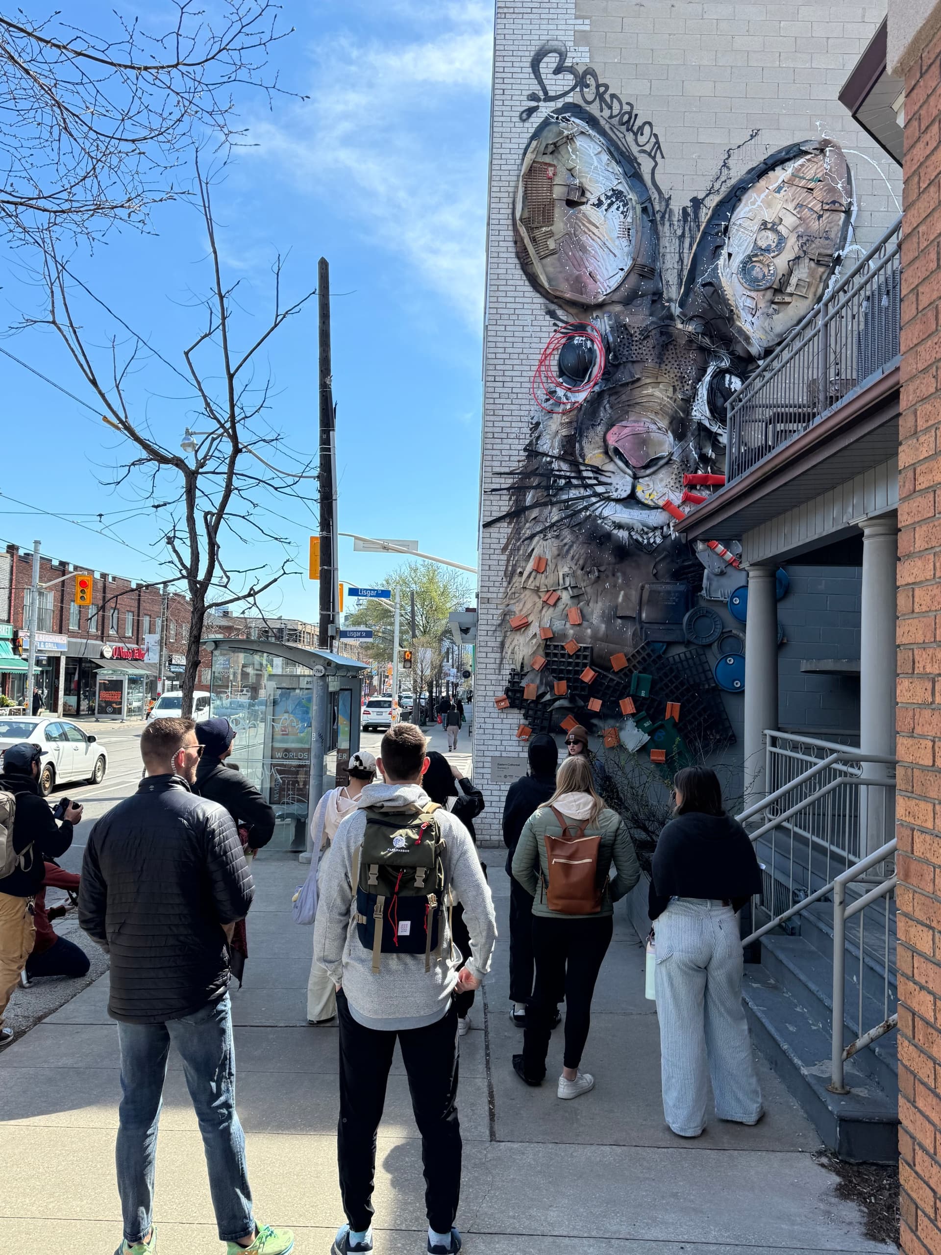 People walking past large street-mural rabbit on urban sidewalk