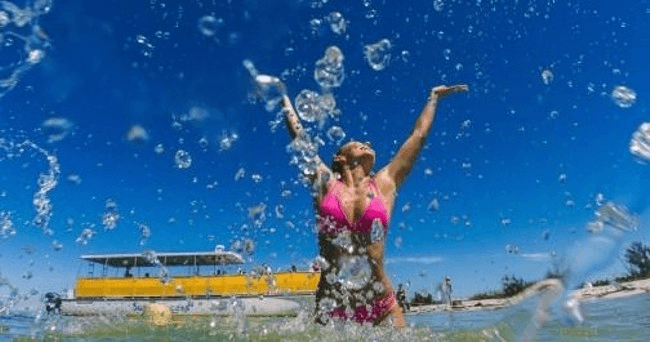 Woman splashing in turquoise surf during sunny beach boat excursion