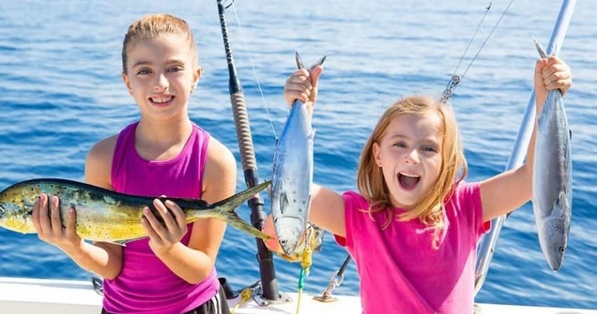 Two girls holding yellowtail fish on charter boat offshore