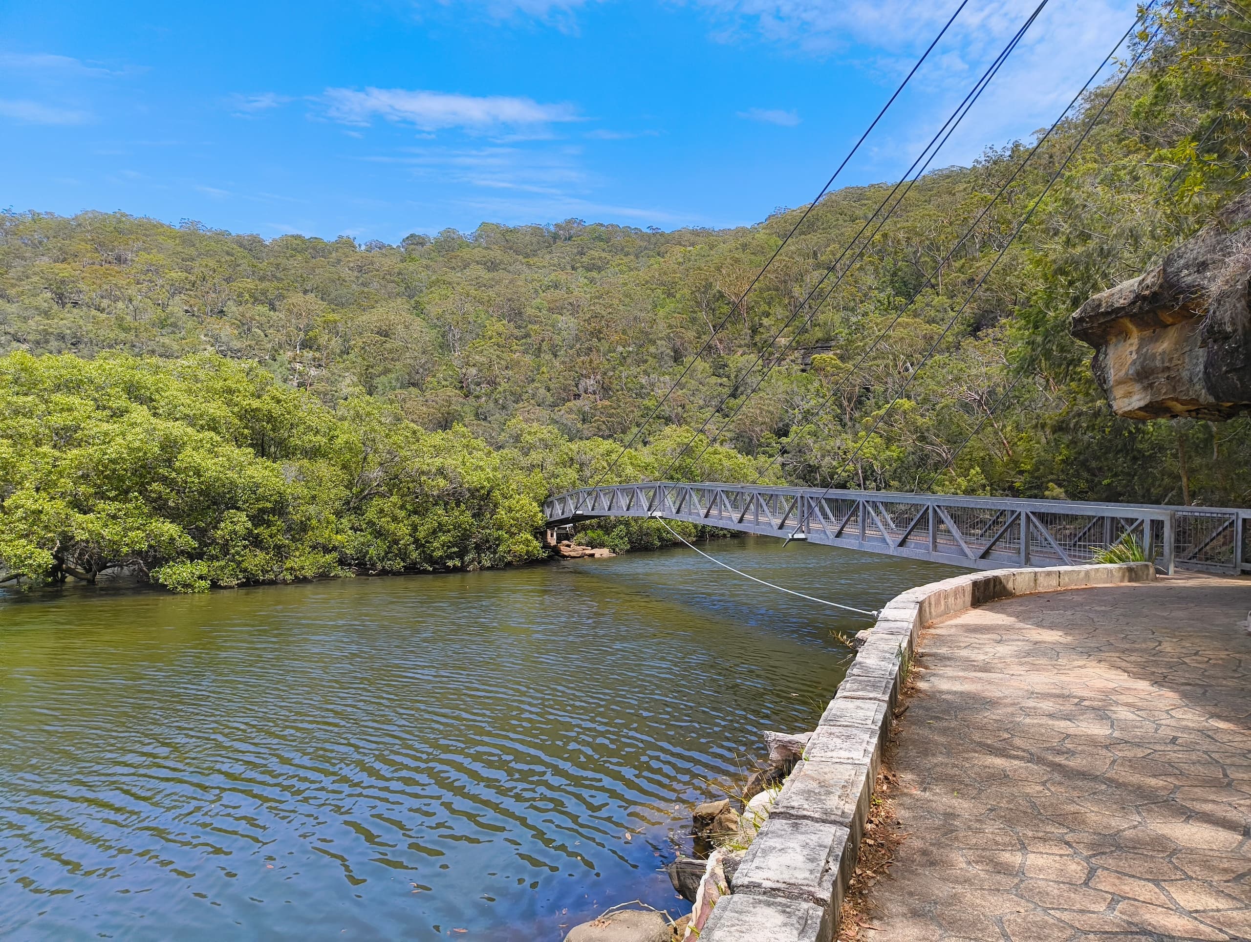 Coastal lakeside trail with pedestrian bridge and river view