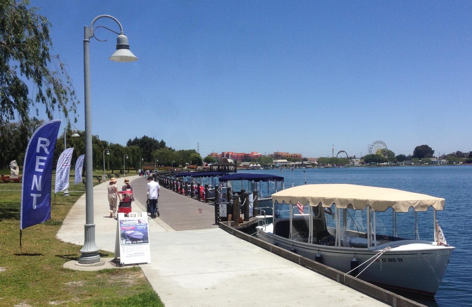 Sunny marina walkway with covered tour boats and open water vista