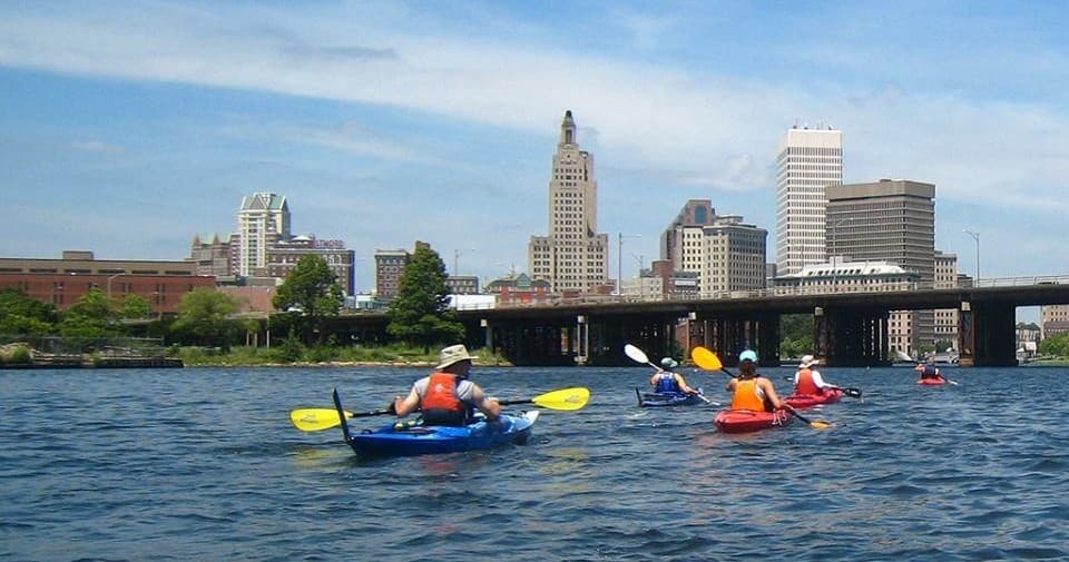 Kayakers paddling on Providence River with city skyline view