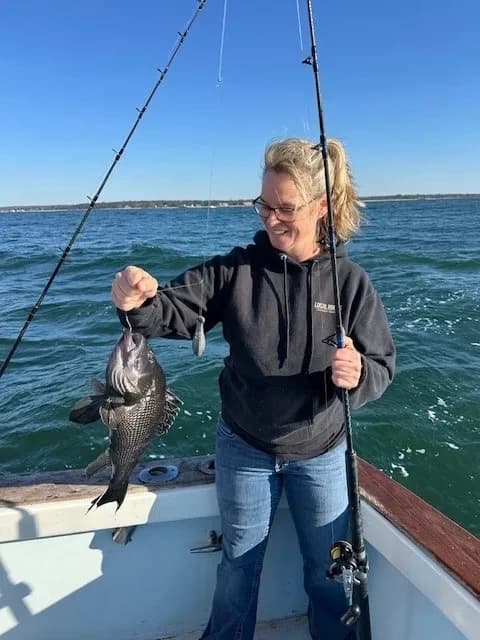 Woman displaying large saltwater fish on charter boat near horizon