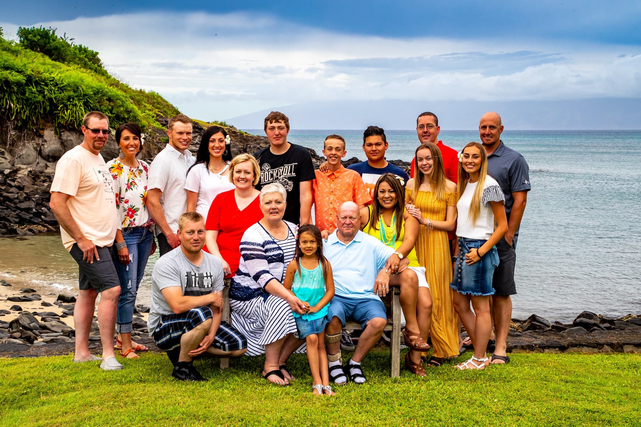 Large family group on grassy coastal bluff with ocean views, posed