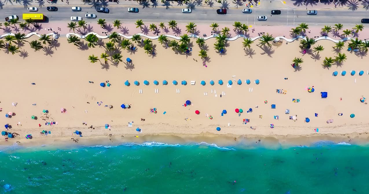 Aerial beach view with umbrellas and ocean shoreline activity