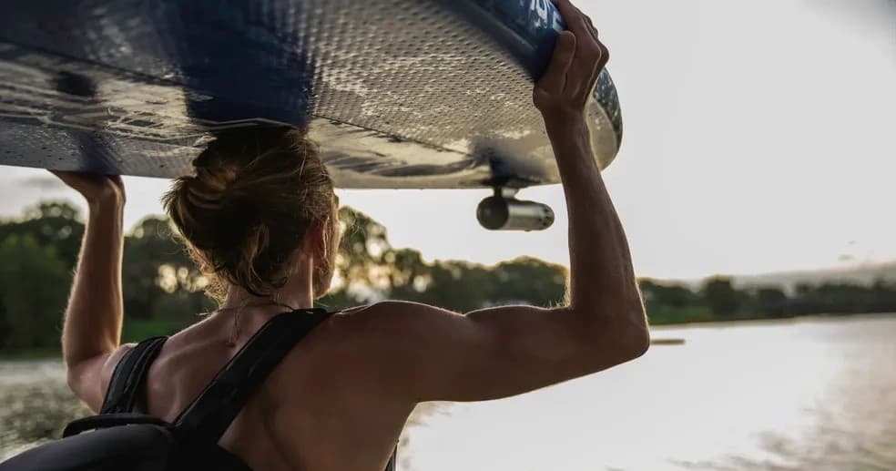 Surfer carrying board to shoreline at sunset for surfing tour