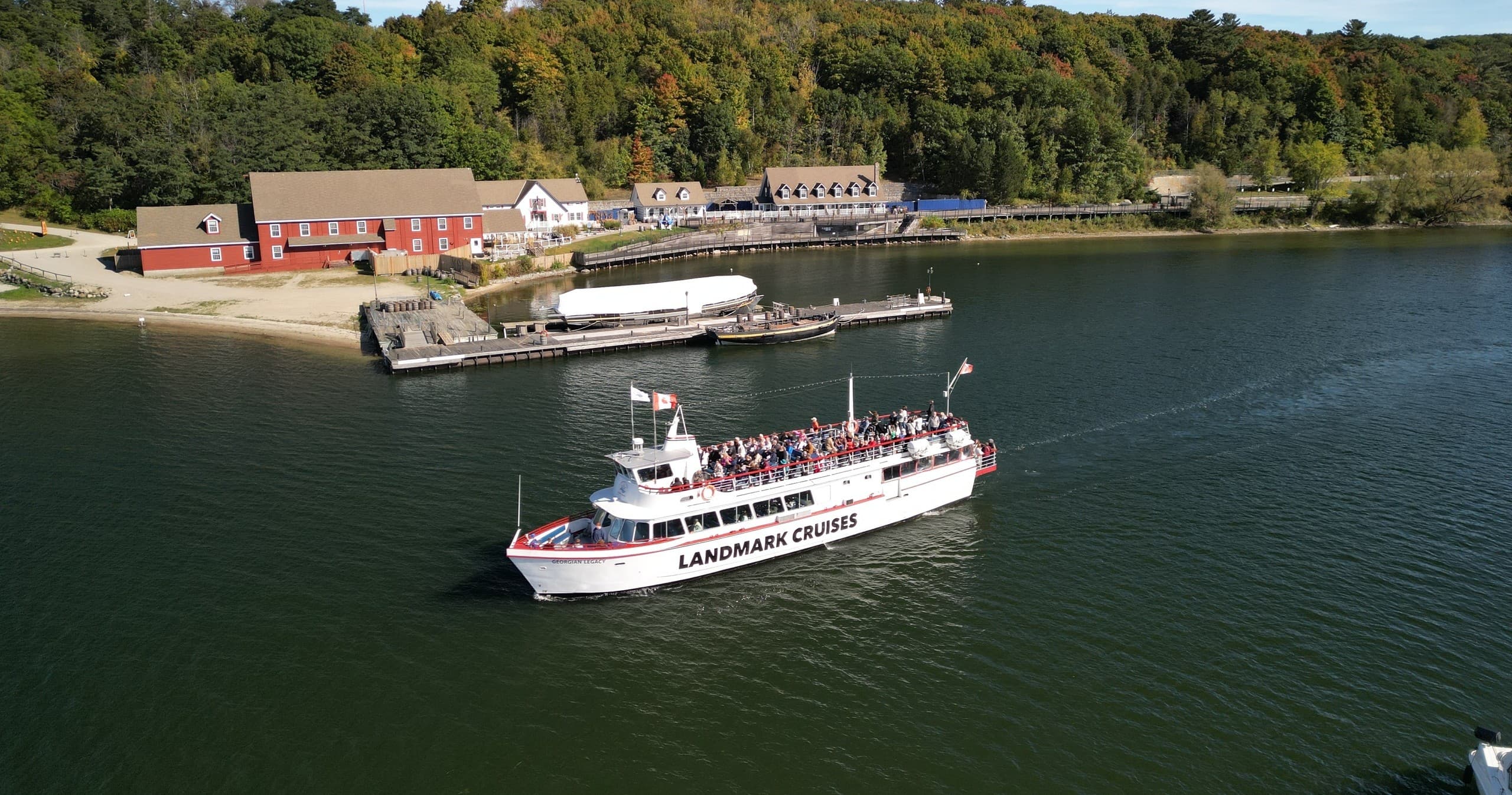 Sightseeing cruise near forested shoreline, passengers on deck