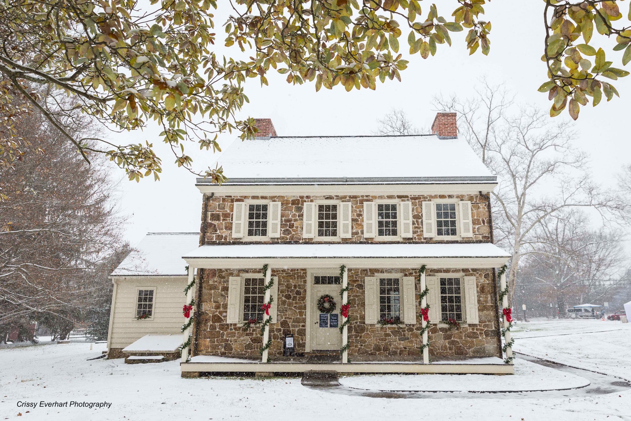 Snow-covered historic house facade at Sugartown with winter grounds