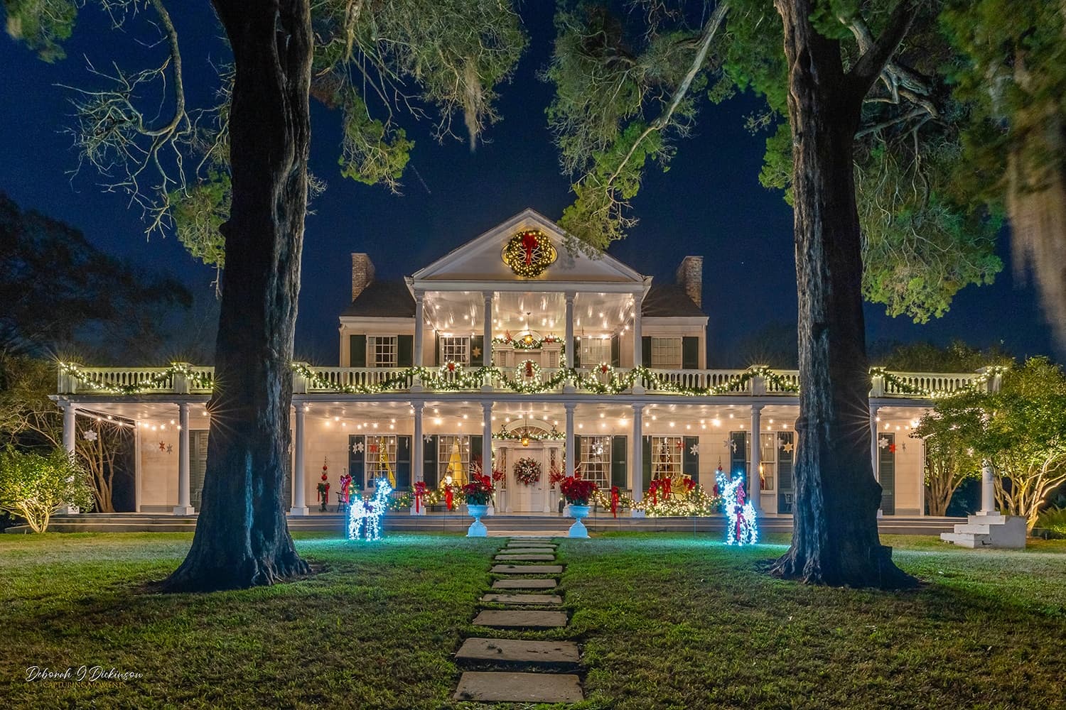 Night-illuminated antebellum mansion grounds with live event