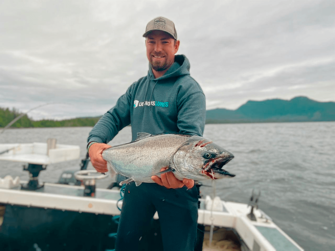 Angler holding large Chinook salmon on coastal boat, open water