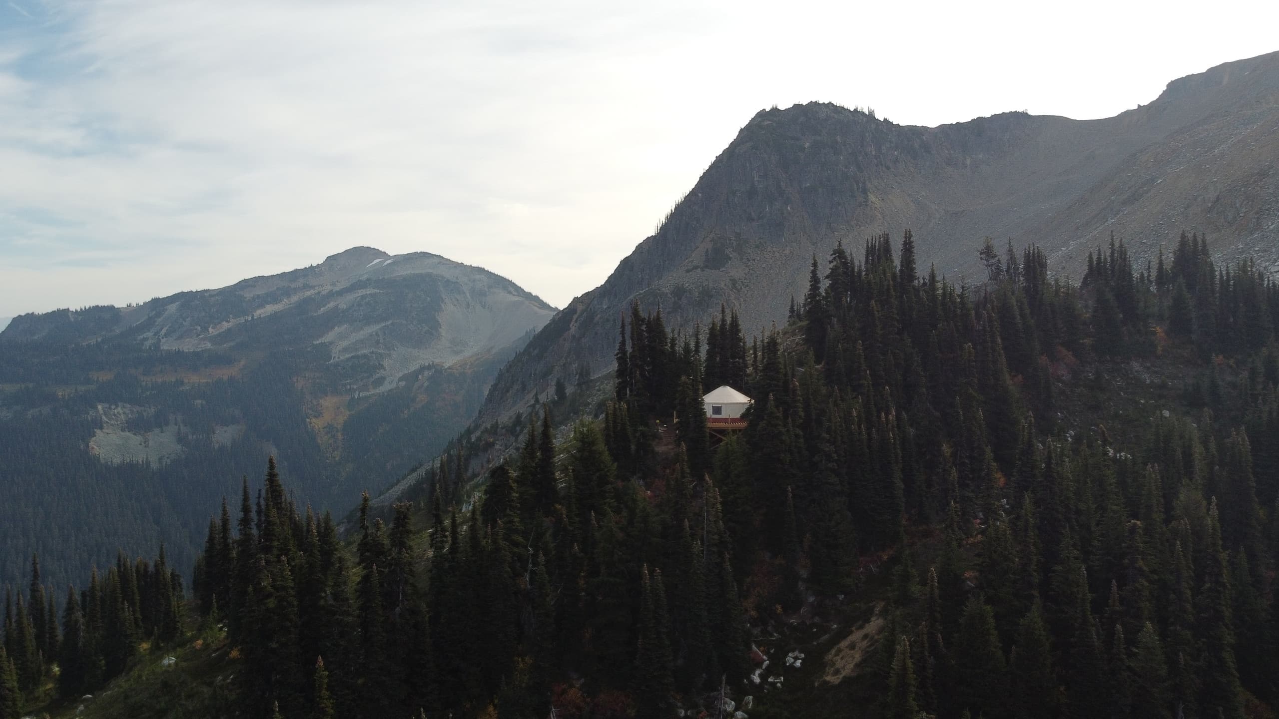Remote mountain cabin among dense evergreen forest and ridgelines