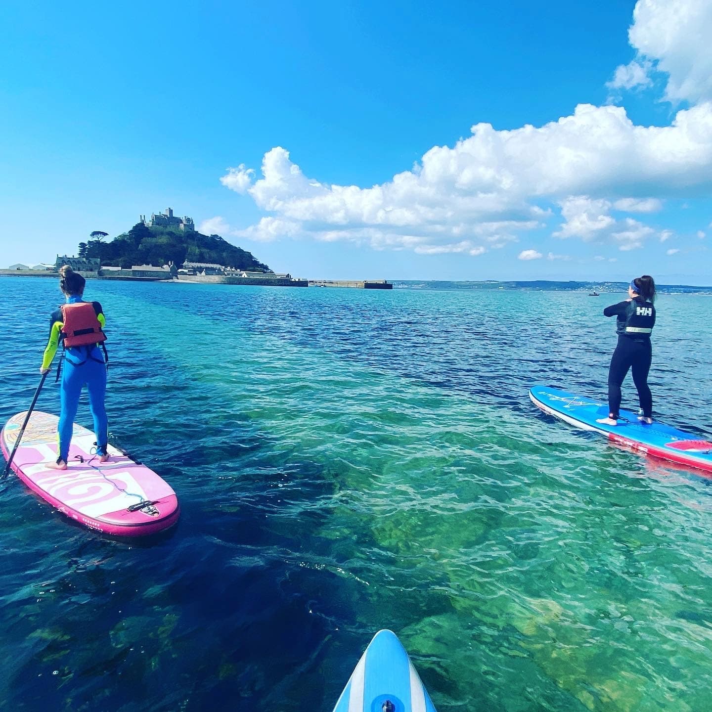 Bright turquoise sea with paddleboarders touring toward island