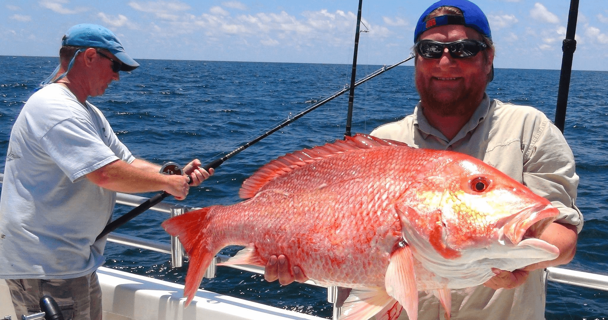 Angler holding giant red snapper on charter boat in open ocean