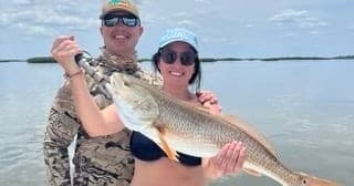 Couple holding large redfish on flats during inshore fishing