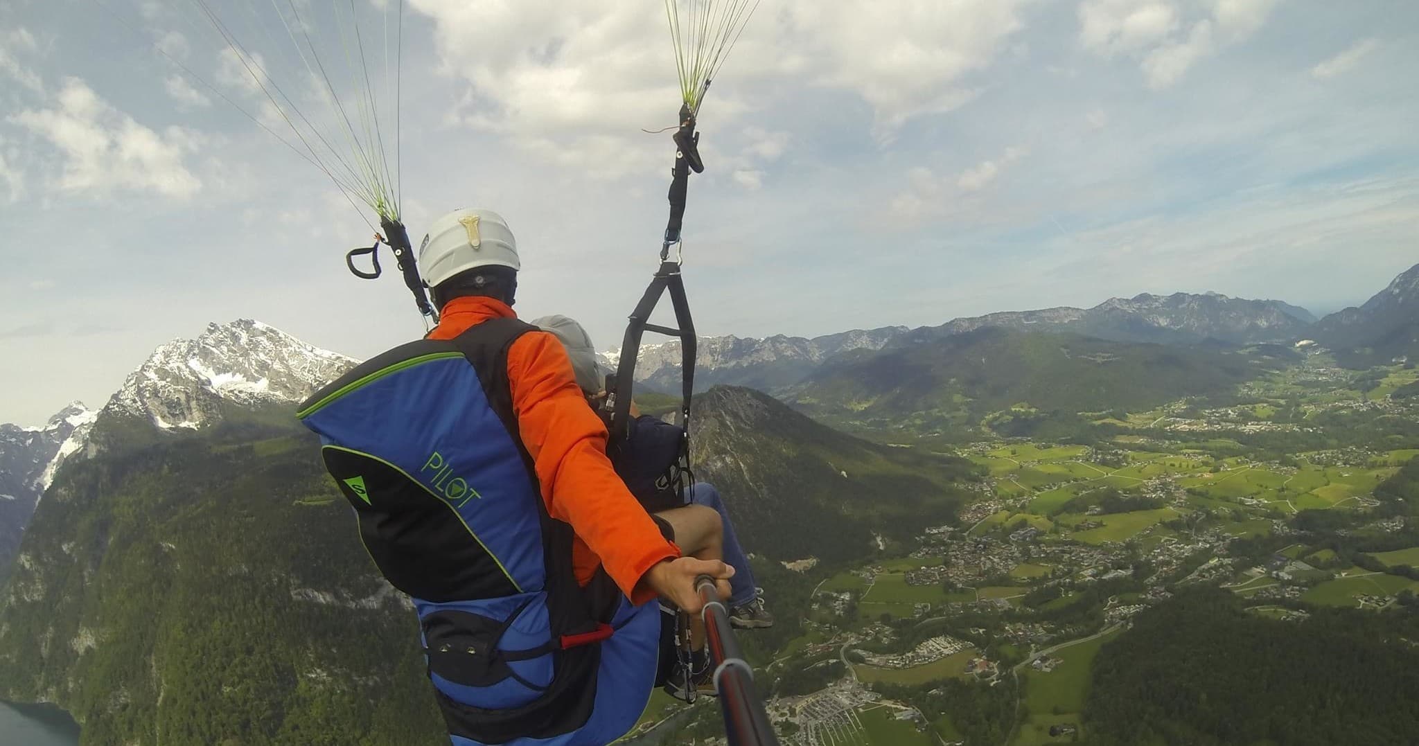 Tandem paragliding over alpine valley with panoramic mountains