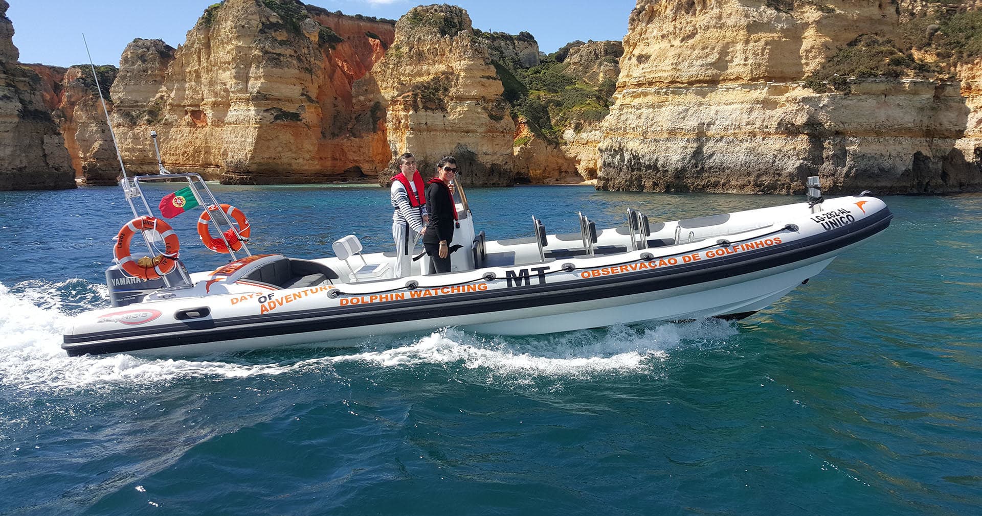 Rigid inflatable boat cruising coastal waters by rock cliffs