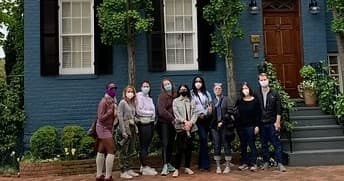 Guided neighborhood walking group posing outside rowhouse